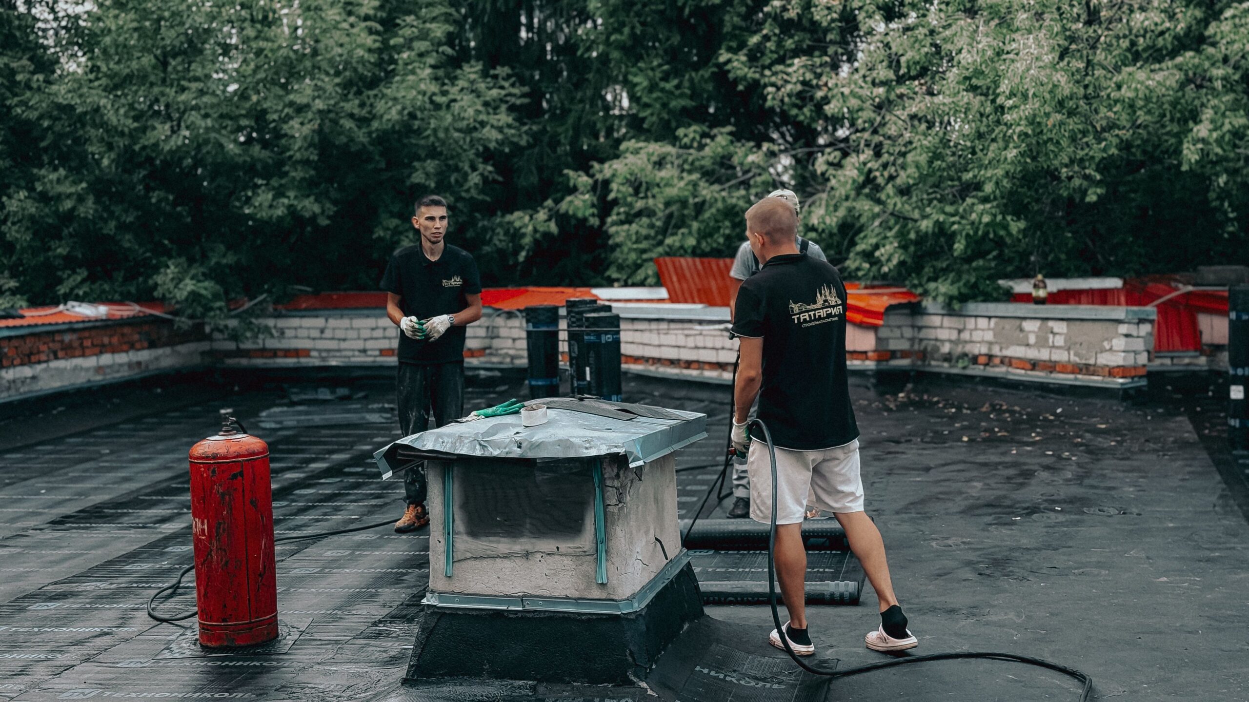 Two roofers inspecting a commercial flat roof during routine maintenance