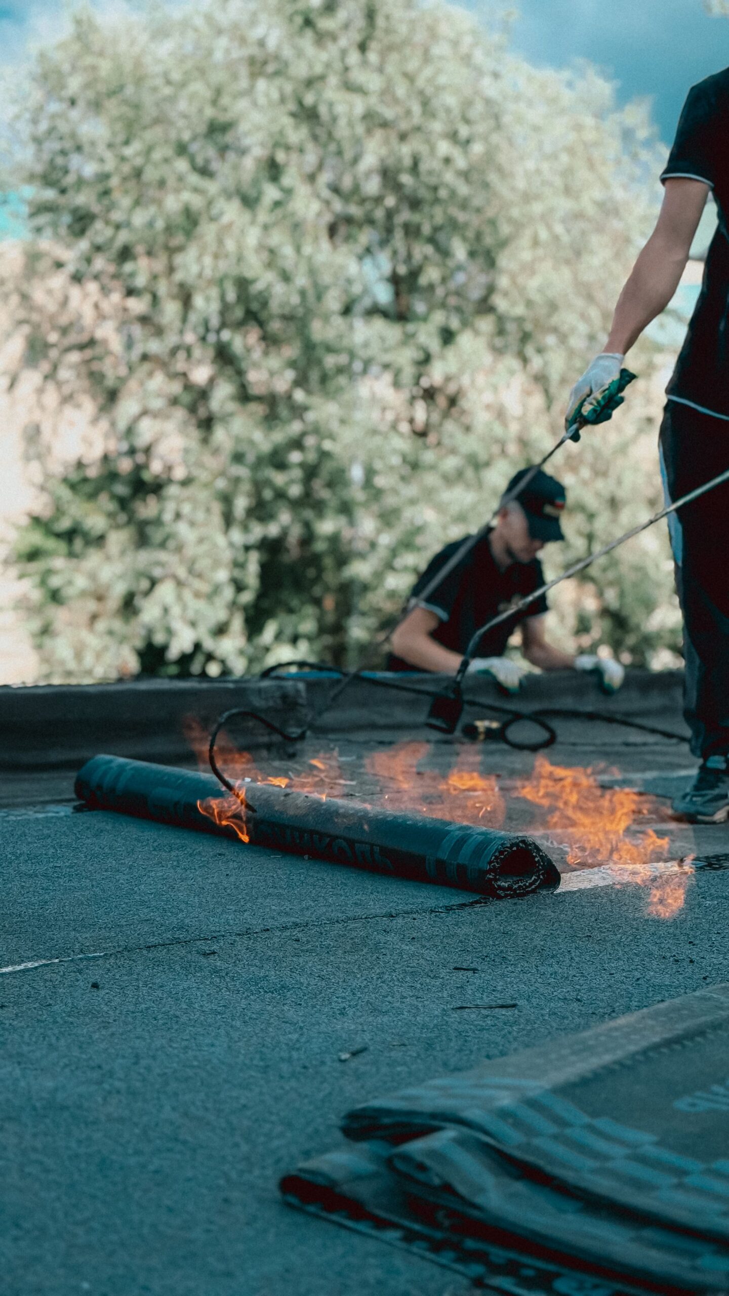 Roofer carrying out a flat roof repair, torch-applying a bitumen membrane