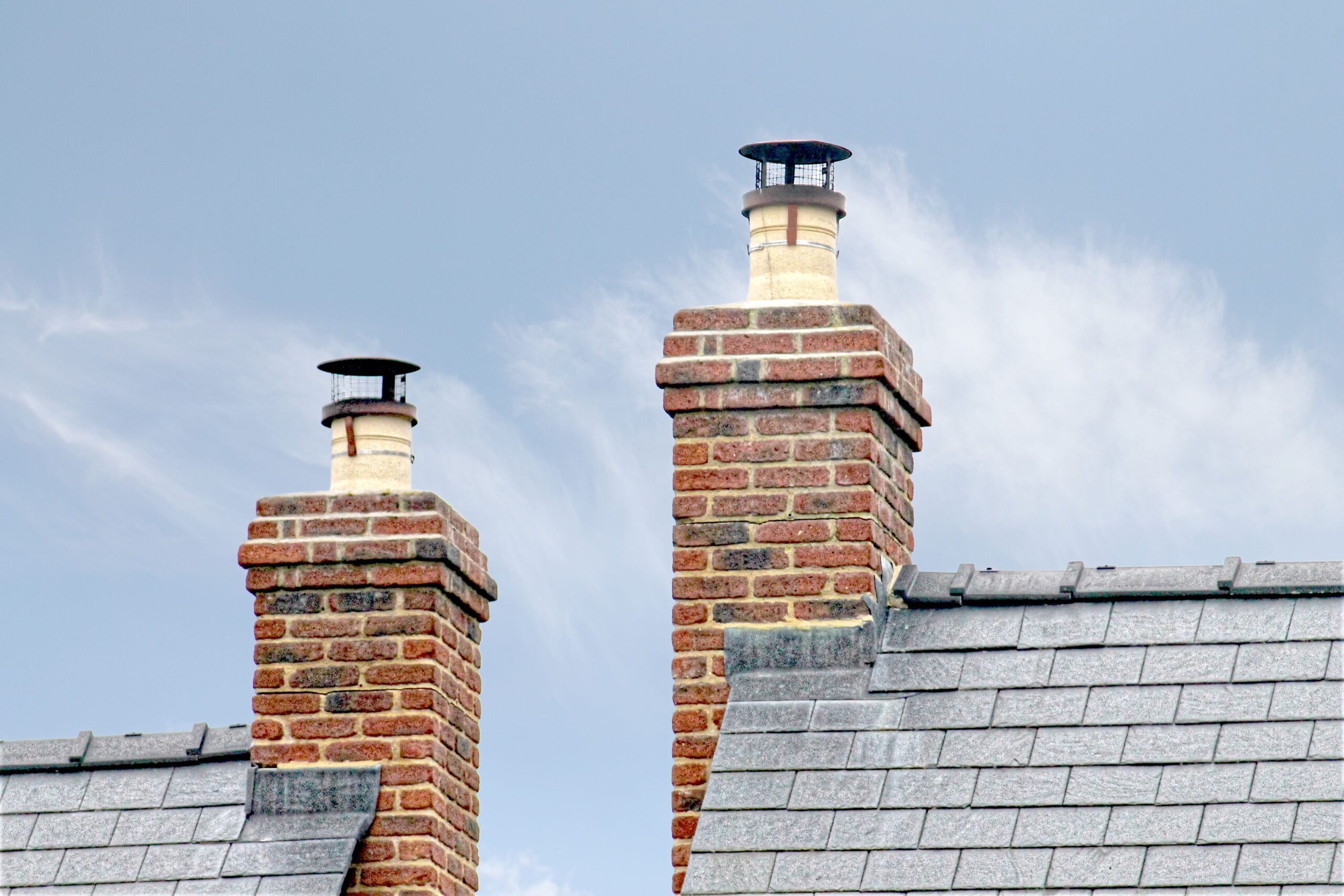 Traditional brick chimney on a UK slate roof, where lead flashing repair is often needed