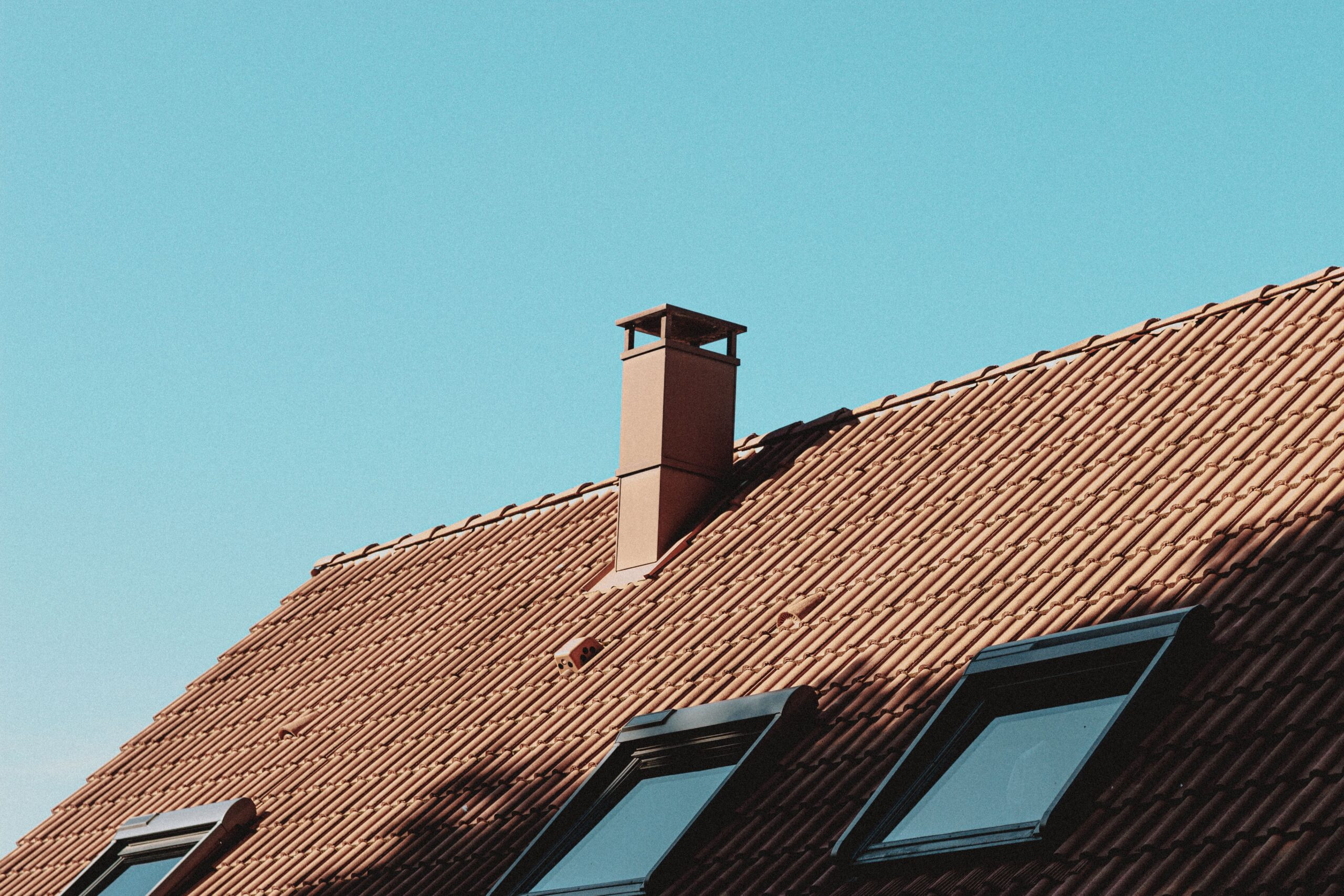 Close-up of a house roof and chimney junction, a common site for flashing failure