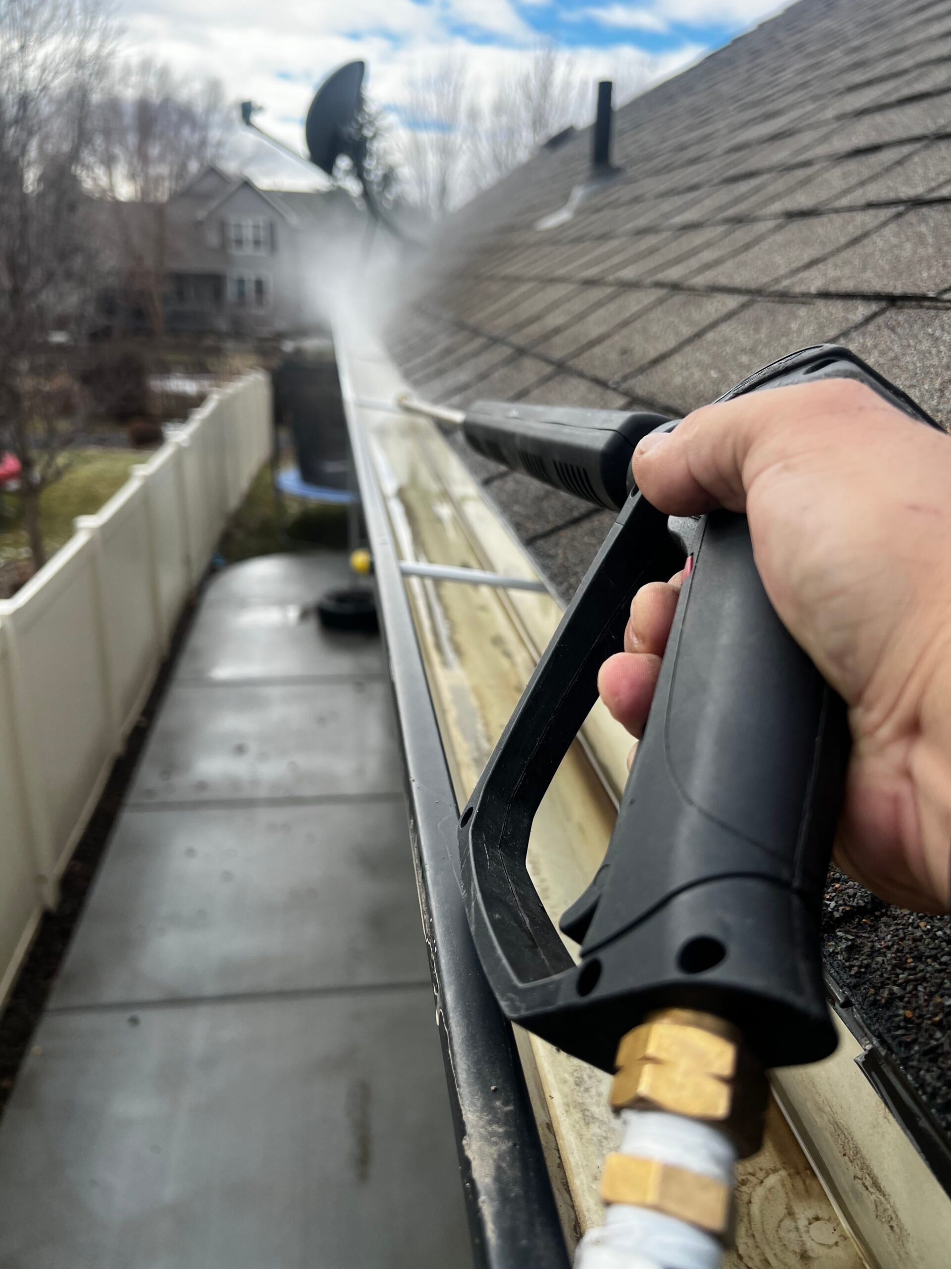 Pressure washing during a gutter and roof cleaning job to remove moss buildup